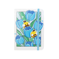 Notebook  formato A6 con copertina rigida e chiusura ad elastico.
Sulla copertina e sul retro sono disegnati dei tulipani blu e delle apette.